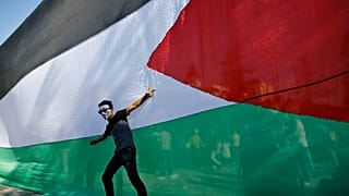 شاب فلسطيني يقف أمام علمه الوطني خلال احتفالات في مدينة غزة. 2017/10/12