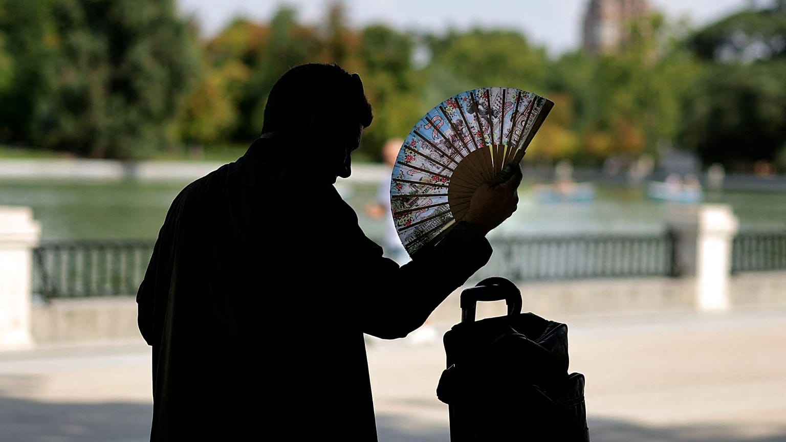 A man uses a hand fan in a park in central Madrid during a heatwave, on August 2, 2022. Heatwaves kill thousands of people every year.