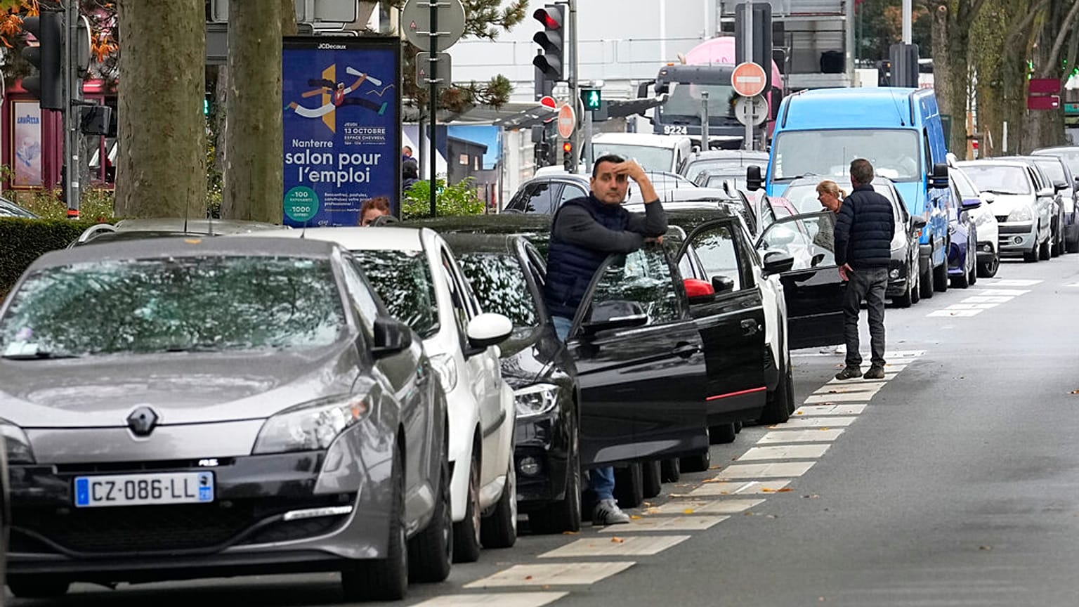 A man stands by his car as he waits to reach a petrol station in Nanterre, France