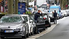 A man stands by his car as he waits to reach a petrol station in Nanterre, France