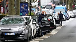 A man stands by his car as he waits to reach a petrol station in Nanterre, France