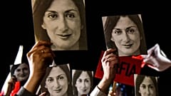  In this file photo taken on November 29, 2019 shows people holding placards reading "Mafia Government" and photos of killed journalist Daphne Caruana Galizia.