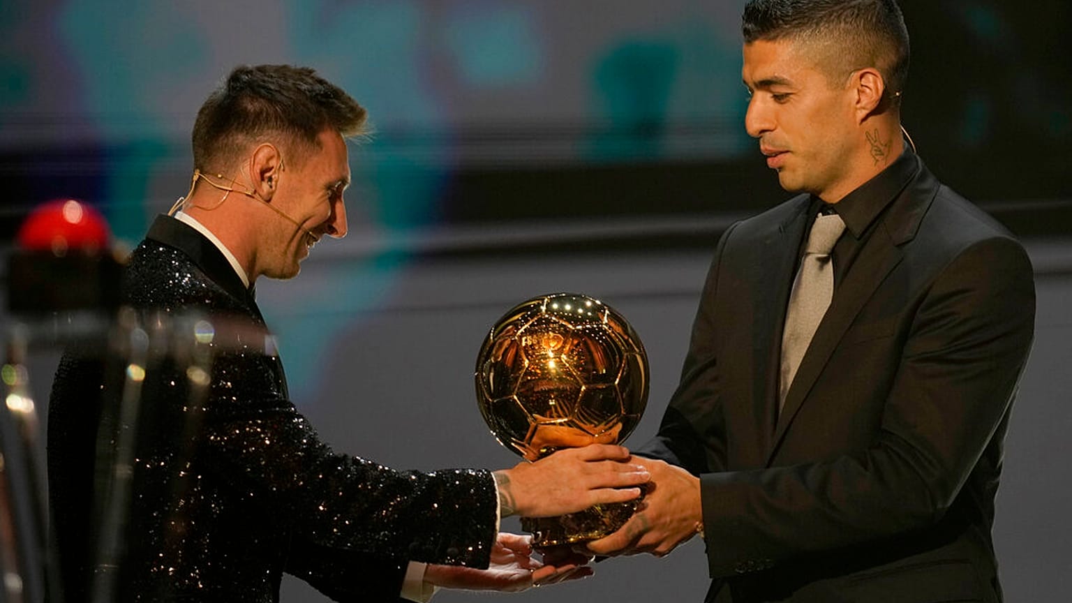 لاعب باريس سان جيرمان ليونيل ميسي يتسلم جائزة الكرة الذهبية 2021 من زميله السابق في برشلونة لويس سواريز خلال حفل الكرة الذهبية 65 في مسرح دو شاتيليه في باريس، 29 نوفمبر 2021