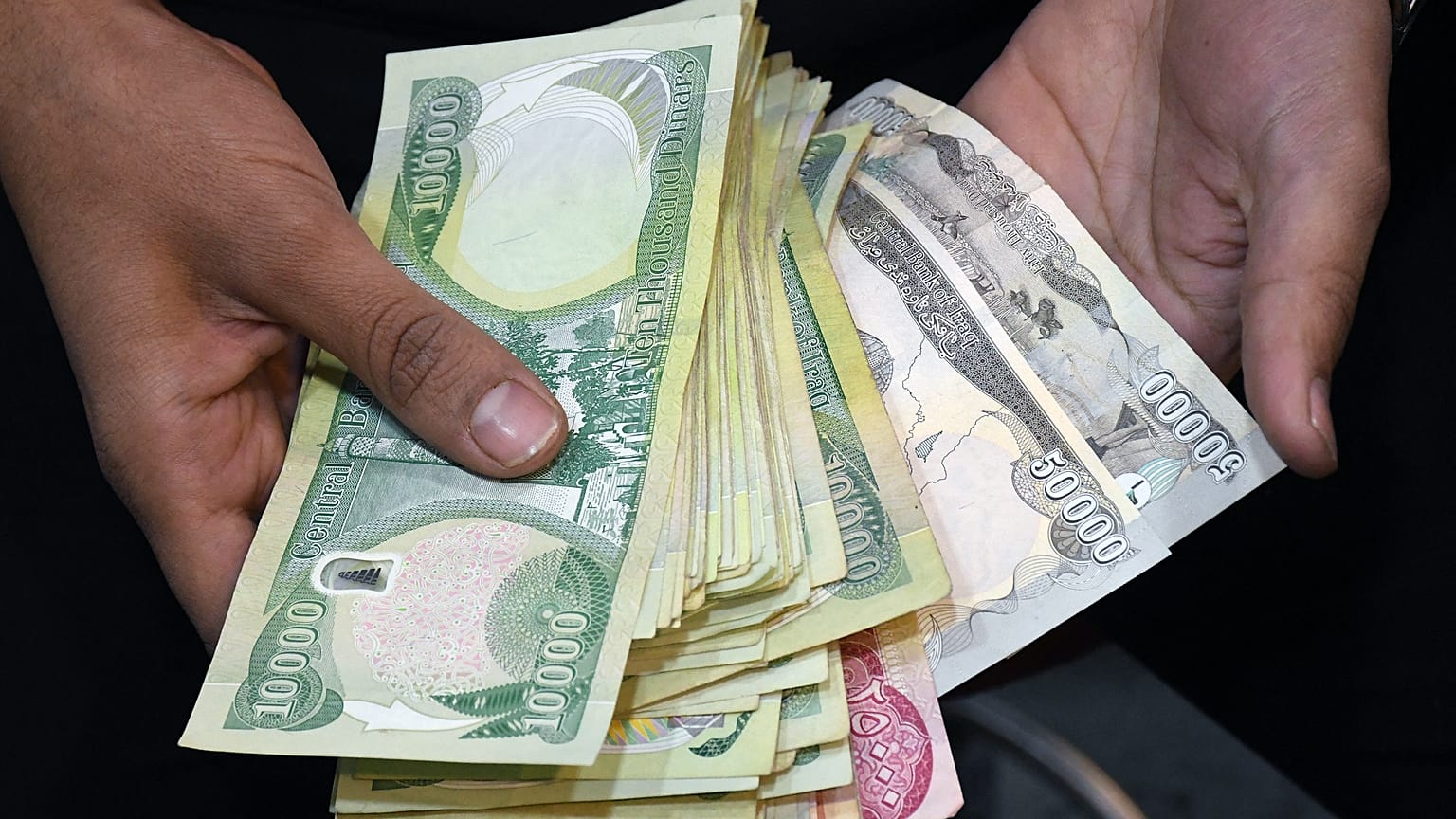 موظف في مكتب صرافة يعرض كومة من الأوراق النقدية بالعملة المحلية في مدينة الناصرية جنوب العراق بمحافظة ذي قار. 2020/01/20