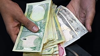 موظف في مكتب صرافة يعرض كومة من الأوراق النقدية بالعملة المحلية في مدينة الناصرية جنوب العراق بمحافظة ذي قار. 2020/01/20