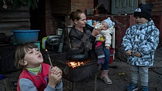 Ukrán nő eteti 9 hónapos gyermekét az ukrajnai Iziumban