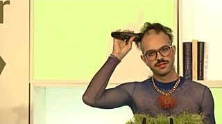 Kim de l'Horizon rasiert sich am Rednerpult die Haare.