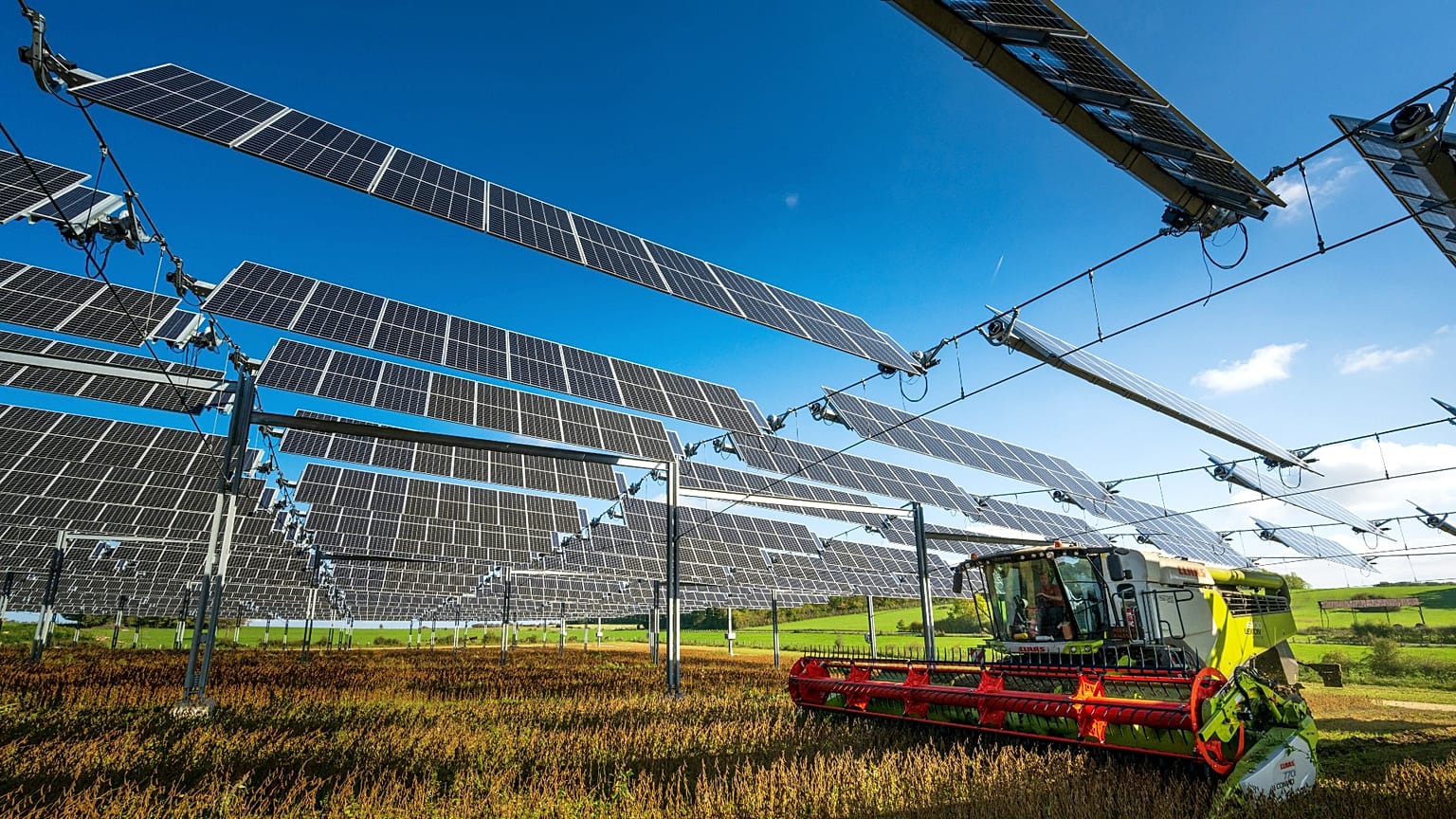 Une moissonneuse-batteuse sous des panneaux solaires suspendus sur un site agrivoltaïque à Amance en France, 12/10/22