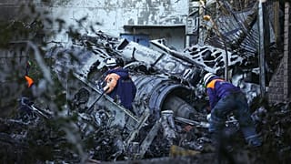 Equipas de socorro examinam partes do avião que se despenhou