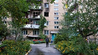 A man walks in front of a building that was damaged by a missile in Irpin, near Kyiv, Ukraine