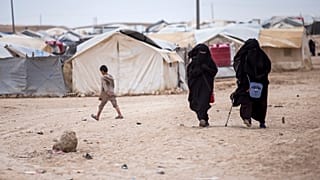 Women walk in the al-Hol camp that houses some 60,000 refugees, including families and supporters of the Islamic State group. 1 May 2021.