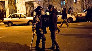 Saturday, Jan. 11, 2020, a protester confronts an Iranian police officer while demonstrators gather in front of Amir Kabir University in Tehran, Iran.