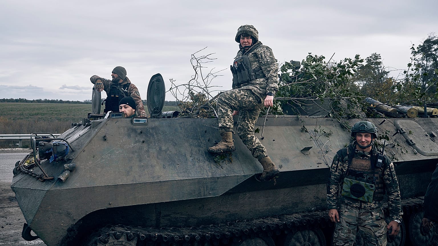 Ukrainian servicemen and a servicewoman, centre, pose for a photo with their armoured vehicle near Bakhmut, 22 October 2022