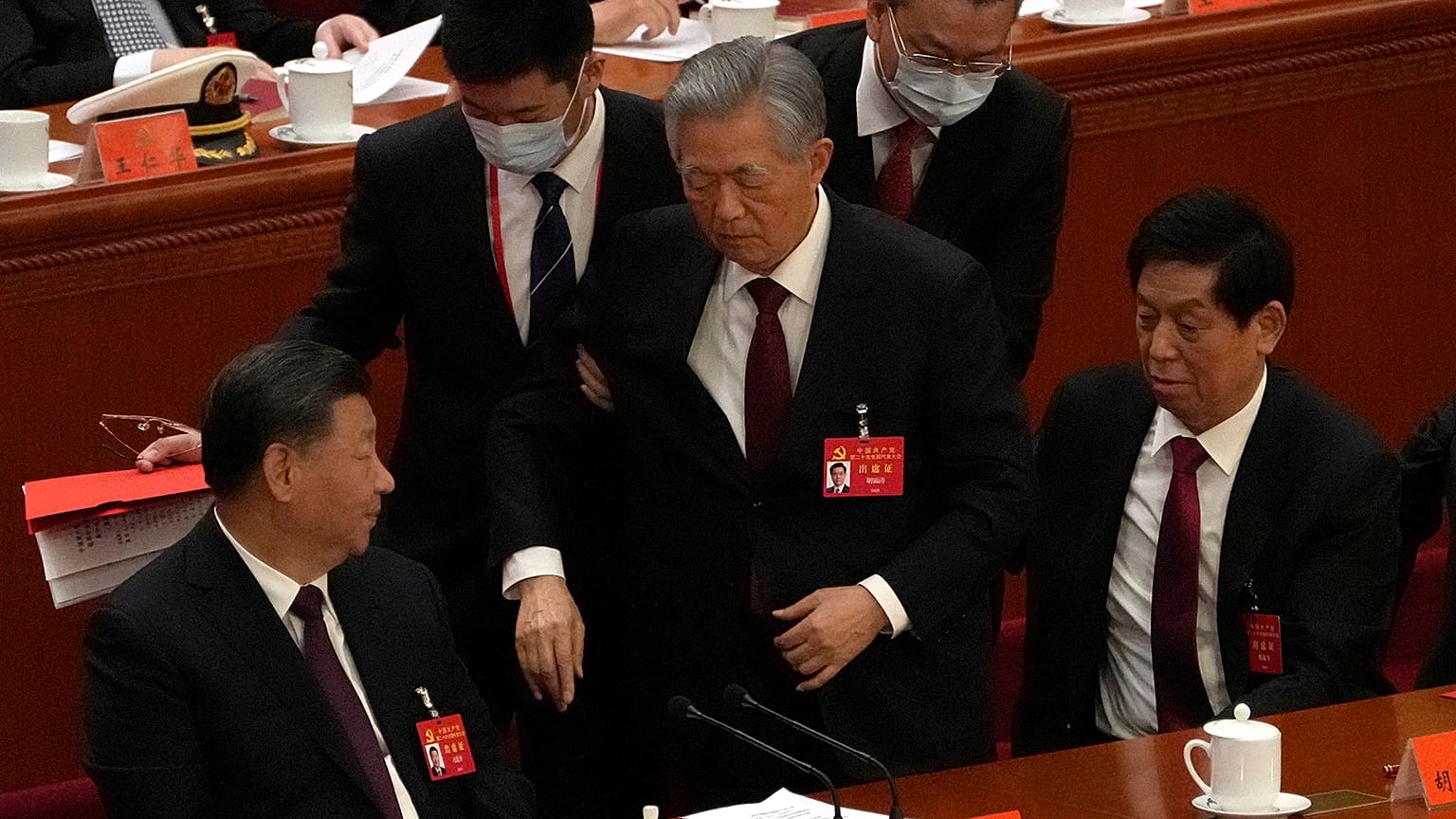 Former Chinese President Hu Jintao, center, is helped during the closing ceremony of the 20th National Congress of China's ruling Communist Party on Saturday, 22 October 2022