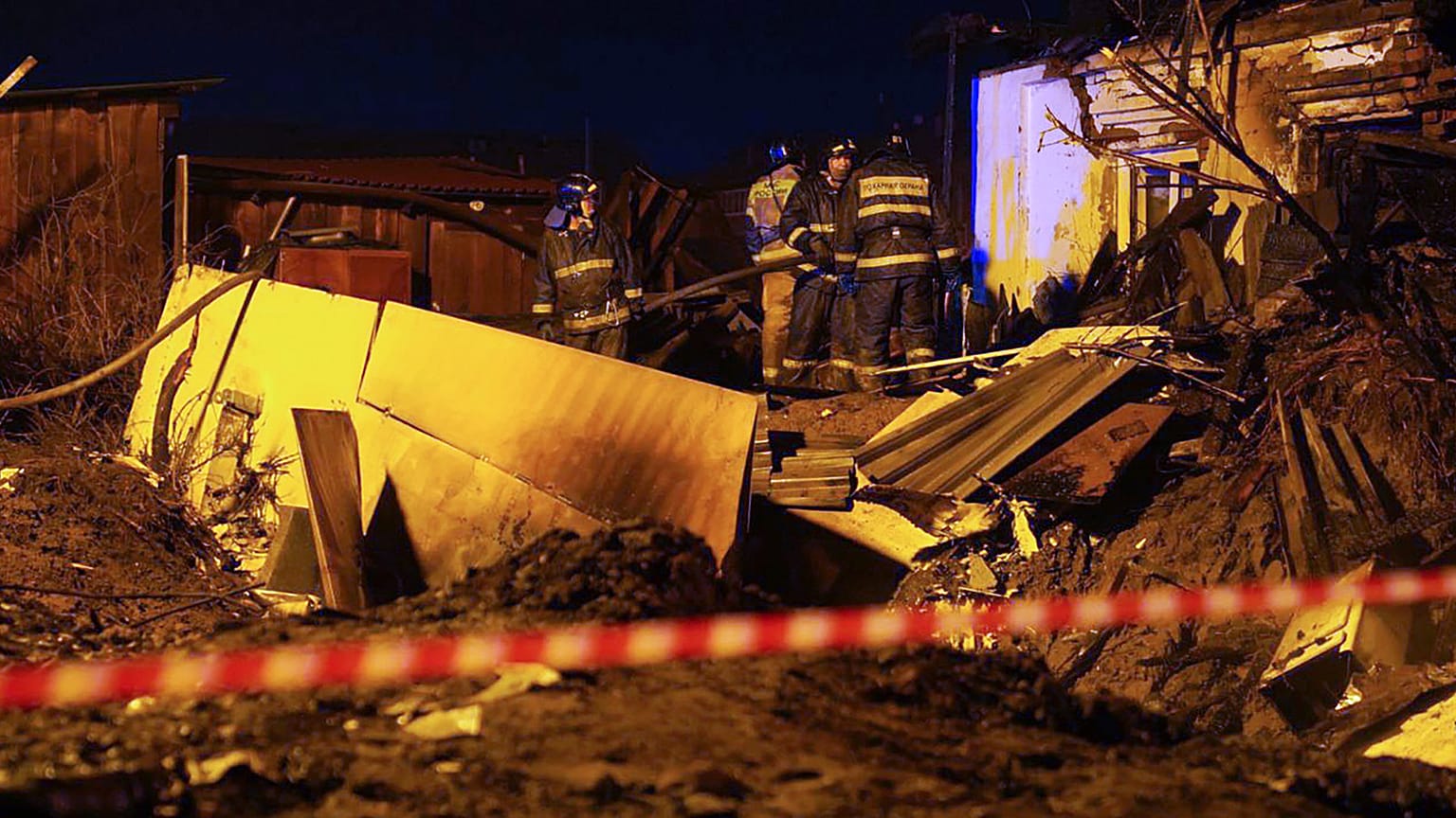 Firefighters work at the scene after a warplane crashed into a residential area in Irkutsk, Russia, Sunday, Oct. 23, 2022. 