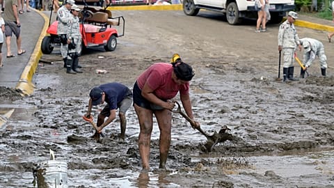 People and emergency brigade clean up mud and water from flooded streets in Sayulita.