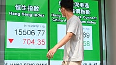 Пешеход проходит мимо знака с цифрами индекса Hang Seng в Гонконге, 24 октября 2022 г. 