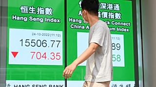 Пешеход проходит мимо знака с цифрами индекса Hang Seng в Гонконге, 24 октября 2022 г. 