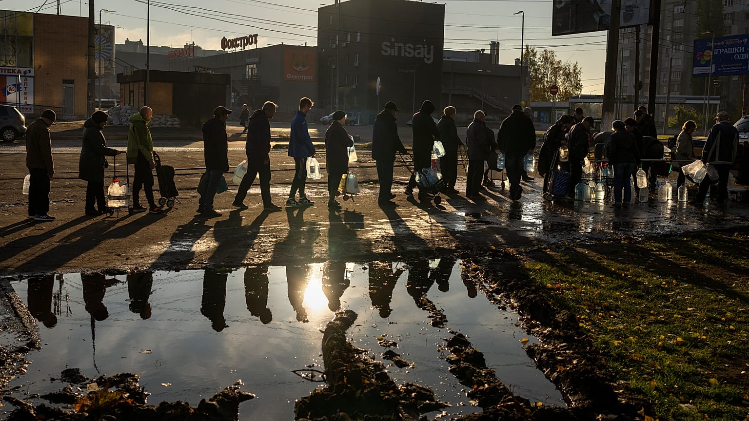 People queuing up hold plastic bottles to refill drinking water from a tank in the center of Mykolaiv.