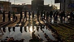 People queuing up hold plastic bottles to refill drinking water from a tank in the center of Mykolaiv.