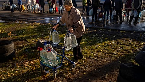 Catherine, 75 ans, pousse son déambulateur chargé de bouteilles en plastique après les avoir remplies dans un réservoir, dans le centre de Mykolaiv - 24.10.2022