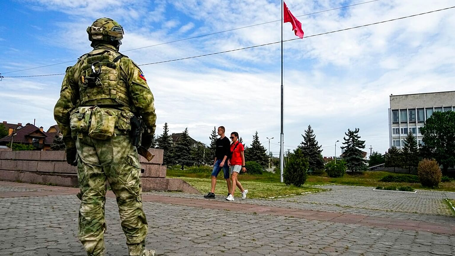  A young couple walks past a Russian soldier in Kherson