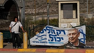 Eski Başbakan Binyamin Netanyahu'nun seçim afişinin önünde otobüs bekleyen bir Yahudi yerleşimci, 