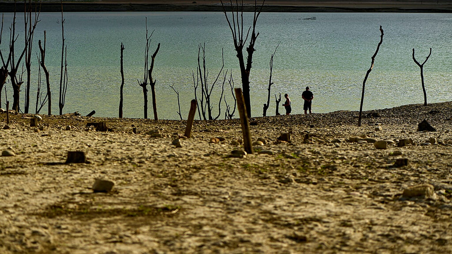 Gente caminando cerca de la frontera en el embalse de Yesa afectado por la sequía, a unos 55 kilómetros de Pamplona, norte de España, 14 de septiembre de 2022.