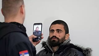 Bir Sırp Mülteciler ve Göç Komiserliği çalışanı, Kuzey Makedonya ile güney sınırına yakın kabul kampında kayıt sırasında bir göçmenin fotoğrafını çekiyor.