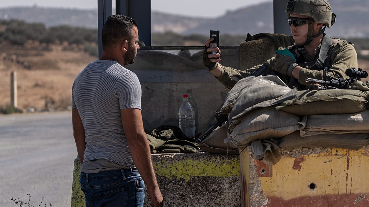جندي من الجيش الإسرائيلي يصور فلسطينيا عند نقطة تفتيش بالقرب من مدينة نابلس بالضفة الغربية