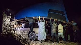 مهربون قرب مدينة الداخلة يحملون قارب صيد مخصص لنقل المهاجرين غير النظاميين إلى جزر الكناري. 2020/12/22