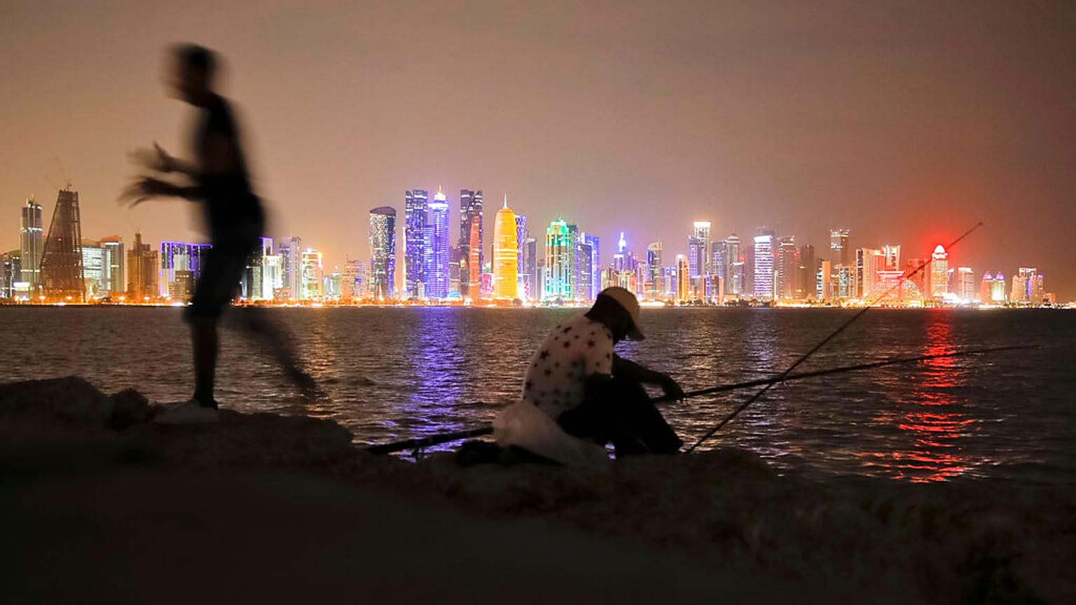 In this Nov. 2, 2018 picture, men fish, backdropped by the city skyline Doha, Qatar.