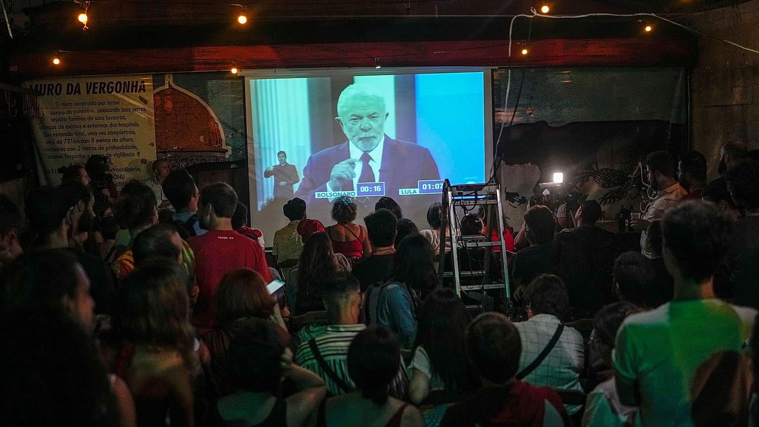 People watch at Bar Al Janiah as Brazil's former President Luiz Inacio Lula da Silva speaks during a televised presidential debate in Sao Paulo, Brazil, Friday, Oct. 28, 2022.