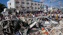 People walk amidst destruction at the scene, a day after a double car bomb attack at a busy junction in Mogadishu, Somalia Sunday, Oct. 30, 2022.