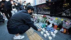 A man offers cups of wine to pay tribute for victims near the scene of a deadly accident in Seoul, South Korea, Sunday, Oct. 30, 2022, after Saturday's Halloween festivities.