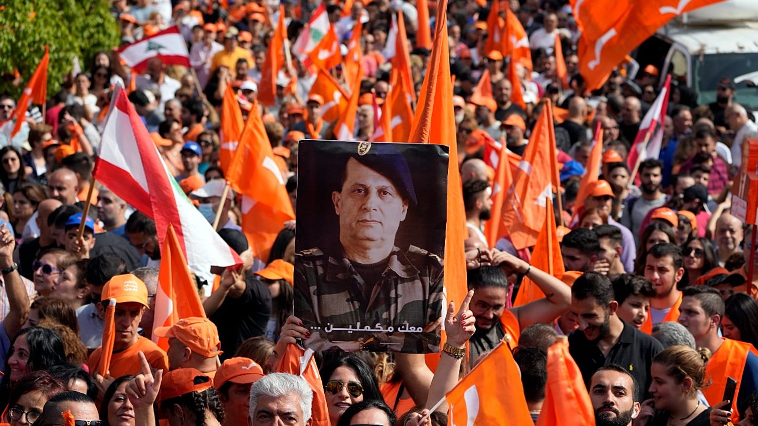 A supporter of Lebanese President Michel Aoun holds his portrait as he delivers a speech outside the presidential palace in Baabda, east of Beirut, Sunday, Oct. 30, 2022.