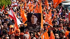 A supporter of Lebanese President Michel Aoun holds his portrait as he delivers a speech outside the presidential palace in Baabda, east of Beirut, Sunday, Oct. 30, 2022.