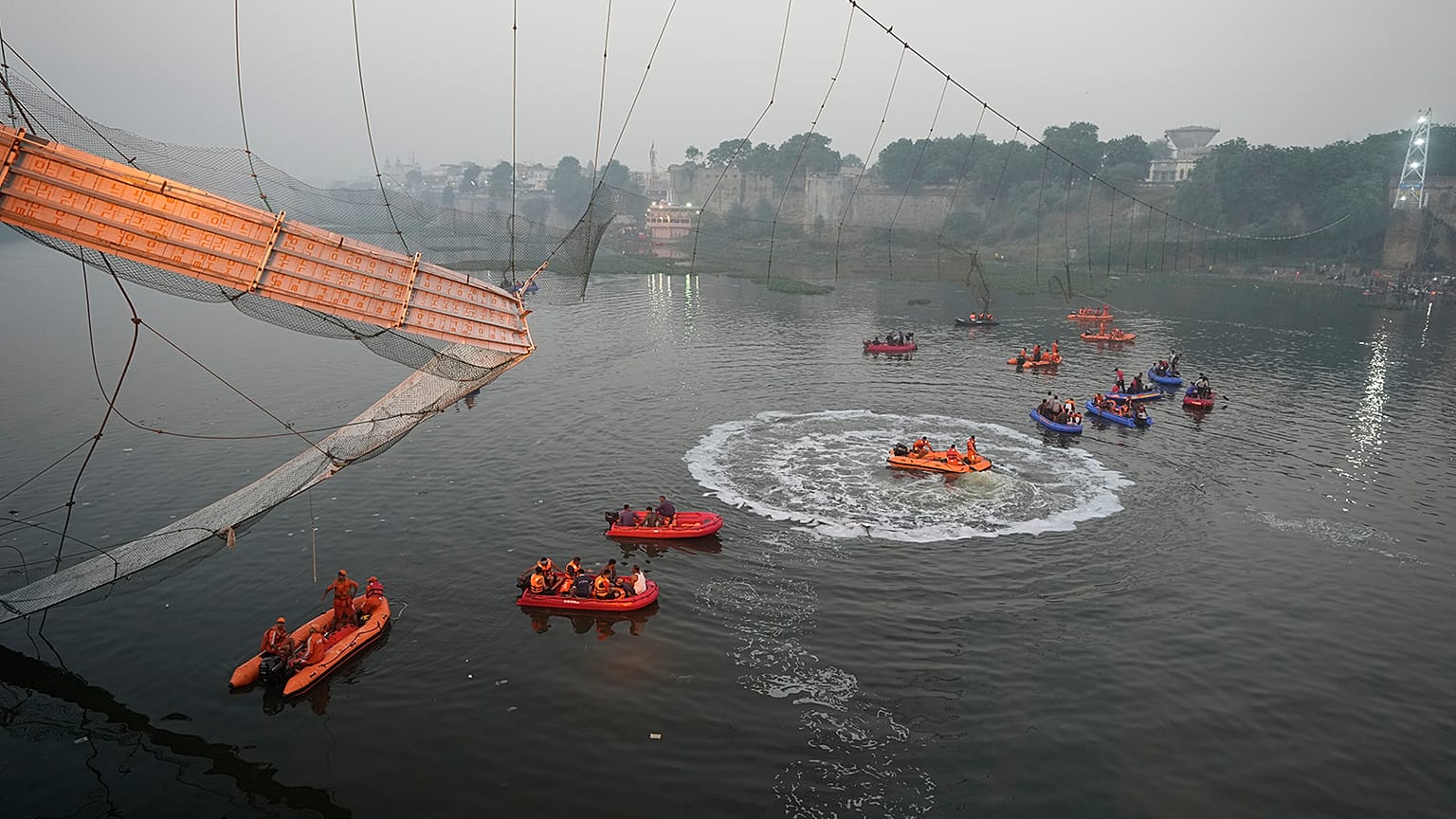 Rescuers on boats search in the Machchu river next to a cable bridge that collapsed in Morbi district, western Gujarat state, India, 31 October 2022.