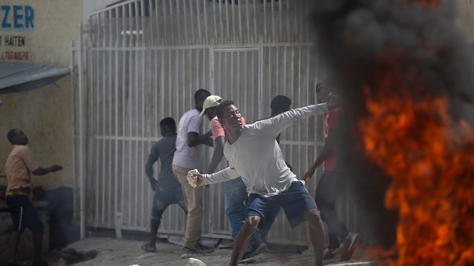 Un manifestante lanza una piedra a la policía durante una protesta por la muerte del periodista Romelson Vilsaint, en Puerto Príncipe, Haití, el domingo 30 de octubre de 2022.