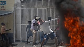 Un manifestante lanza una piedra a la policía durante una protesta por la muerte del periodista Romelson Vilsaint, en Puerto Príncipe, Haití, el domingo 30 de octubre de 2022.