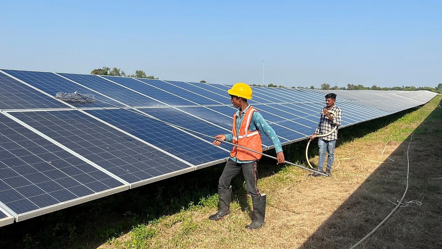 Workers clean panels at a solar park in Modhera.