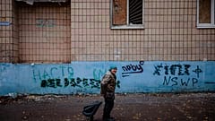 An elderly woman pulls a cart as she walks in the centre of the frontline town of Bakhmut, in eastern Ukraine's Donetsk region, on October 27, 2022,