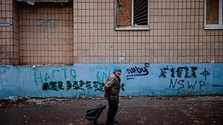 An elderly woman pulls a cart as she walks in the centre of the frontline town of Bakhmut, in eastern Ukraine's Donetsk region, on October 27, 2022,