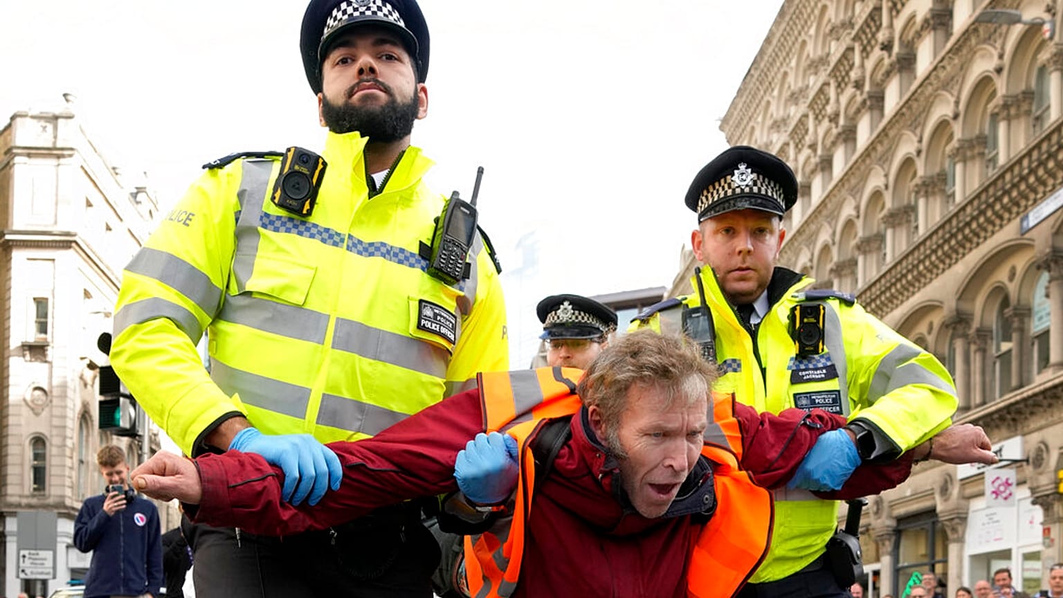 Police officers arrest an activisit from the group Just Stop Oil after they blocked a road in London, Thursday, Oct. 27, 2022.