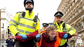 Police officers arrest an activisit from the group Just Stop Oil after they blocked a road in London, Thursday, Oct. 27, 2022.