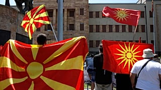 Old and current national flags are waved in front of the parliament building in Skopje.