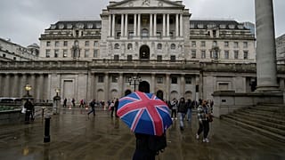 A woman with an umbrella stands in front of the Bank of England, at the financial district in London, Thursday, Nov. 3, 2022.