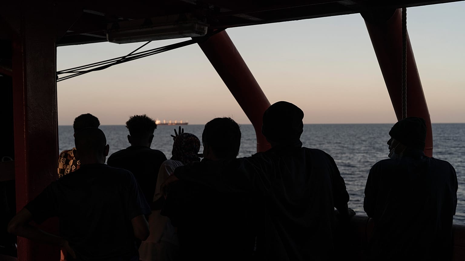 Migrants rescued in the Mediterranean Sea stand onboard of the Ocean Viking rescue ship.
