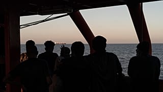 Migrants rescued in the Mediterranean Sea stand onboard of the Ocean Viking rescue ship.