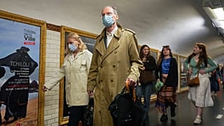 People wearing face masks to protect against COVID-19 rushes to a subway platform in Paris.